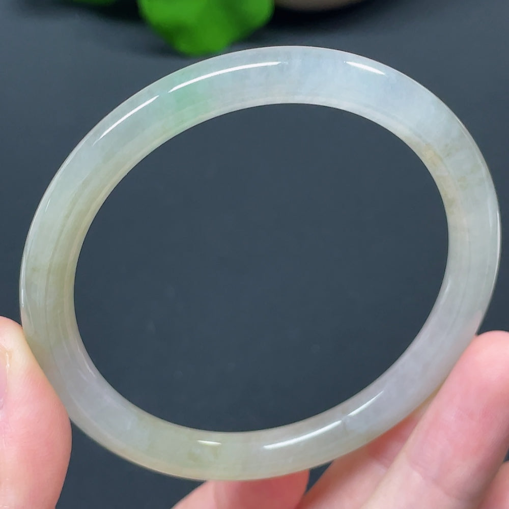 Round jadeite bangle with smooth, polished surface, crafted by HKHQ, showcasing vibrant green jade color and elegant design.