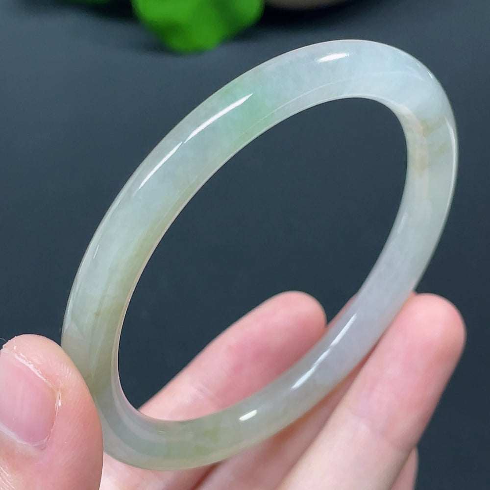Smooth jadeite round bangle from HKHQ featuring a polished green jade surface, showcasing elegant craftsmanship and natural stone texture.
