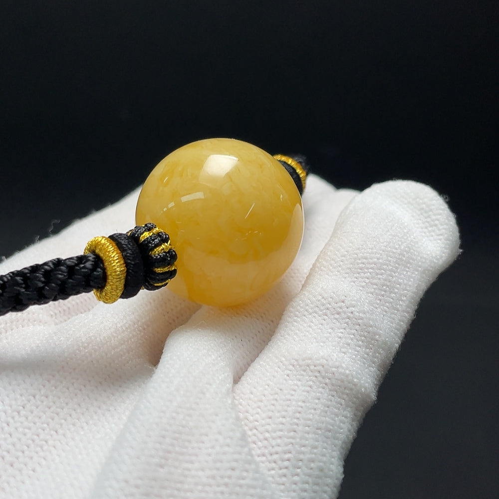 Amber beeswax pendant necklace with cord, approximately 25.2mm in size and 14.39g, from HKHQ.