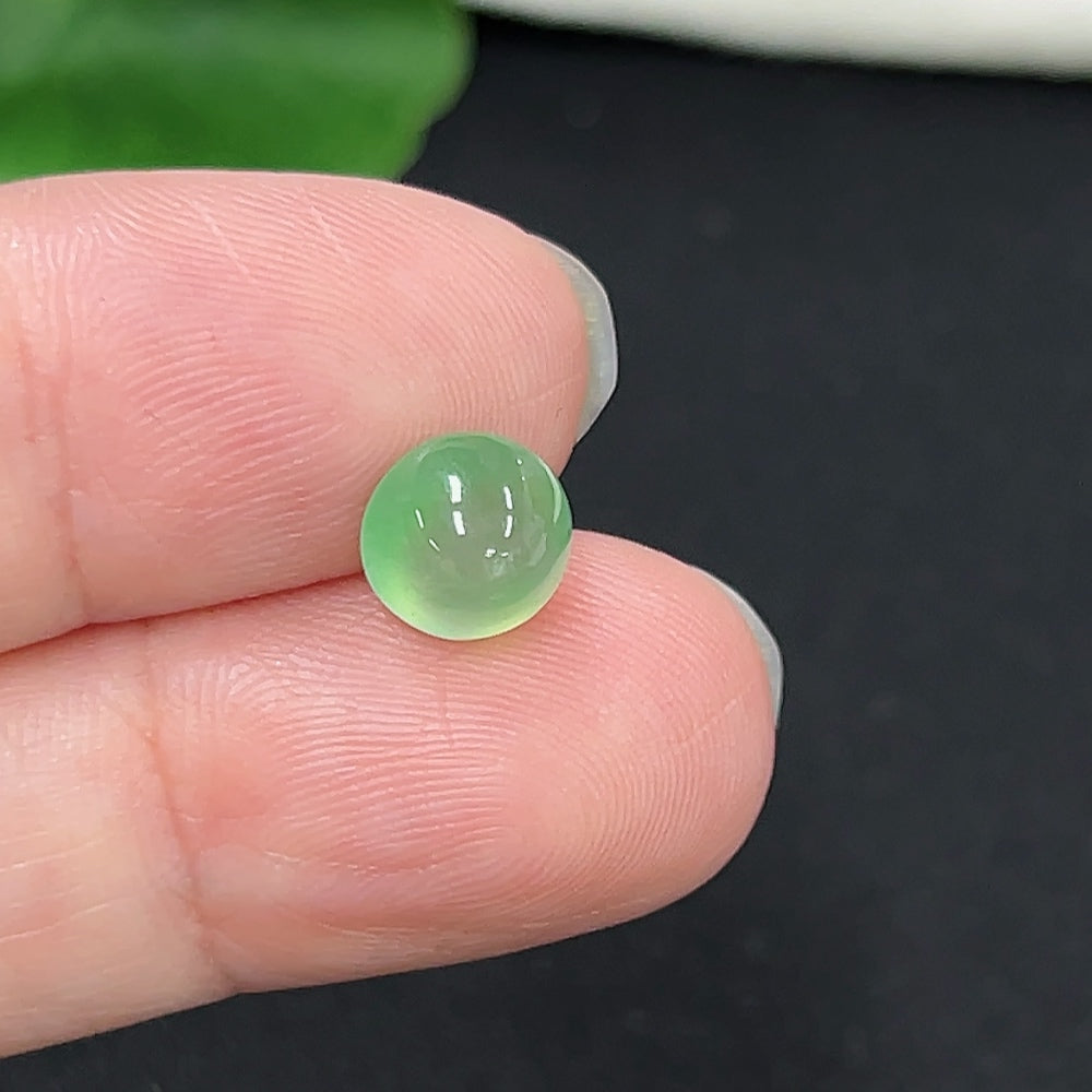Small jadeite cabochon gemstone, approximately 0.3g, set in jewelry by HKHQ, showcasing smooth, polished green jadeite.
