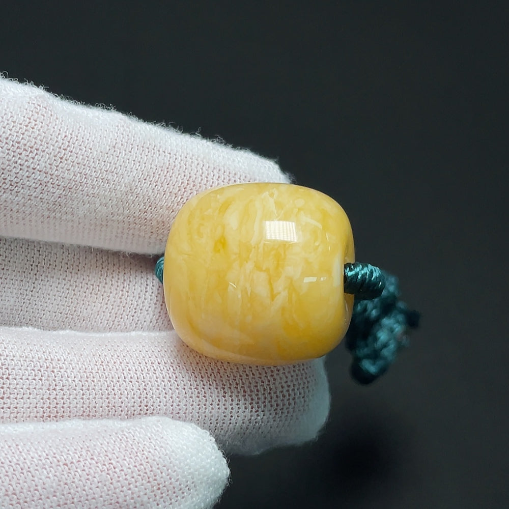 Amber beeswax pendant from HKHQ with natural amber color, weight approximately 10.99g, shown hanging on a cord.