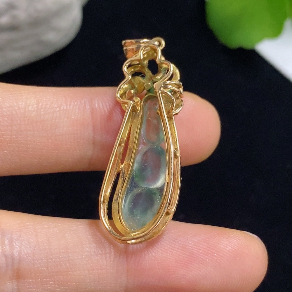 Jadeite Auspicious Bean pendant with diamond accents, 18k gold, displayed close-up showing intricate inlay and polished surface.