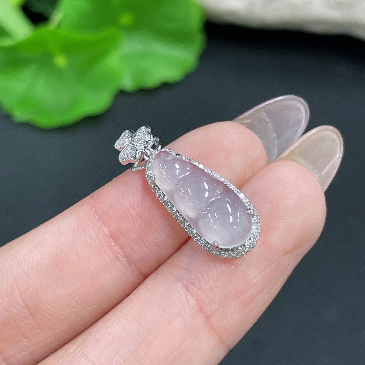 Jadeite pendant in bean shape with 18k gold inlay and diamond accents, weighing approximately 1.4 grams.
