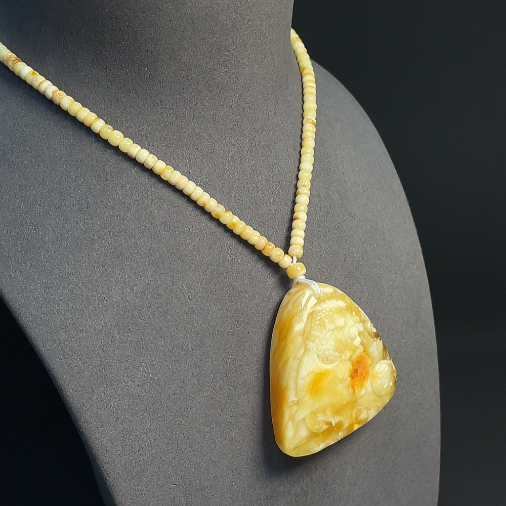 Amber beeswax pendant with colorless coating, partial repairs visible, weighing about 35.77g, from HKHQ with collection certificate.