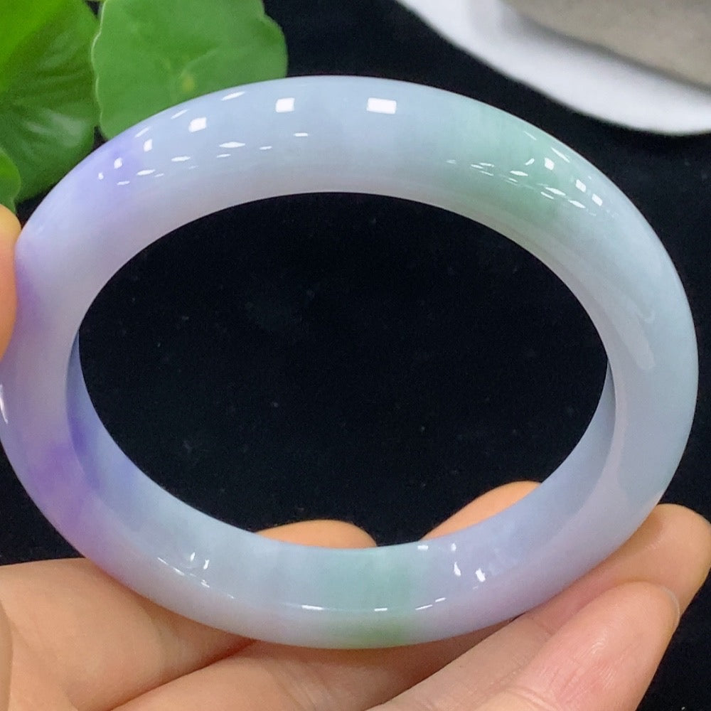 HKHQ jadeite bangle in size 59.3 with a weight of 70.2g, showcasing smooth, polished green jade with intricate natural patterns.