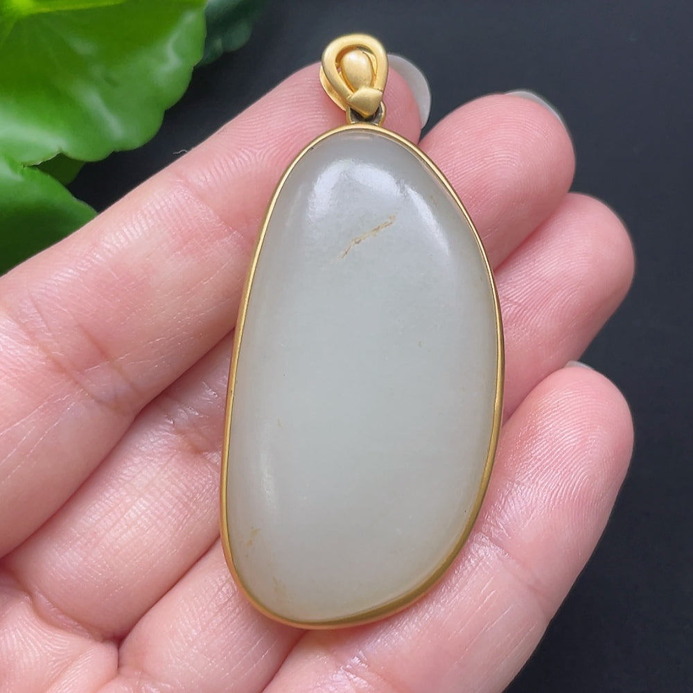 Hetian jade inlaid pendant with 18K gold setting, displayed on a necklace, showcasing intricate craftsmanship and rich green jade.