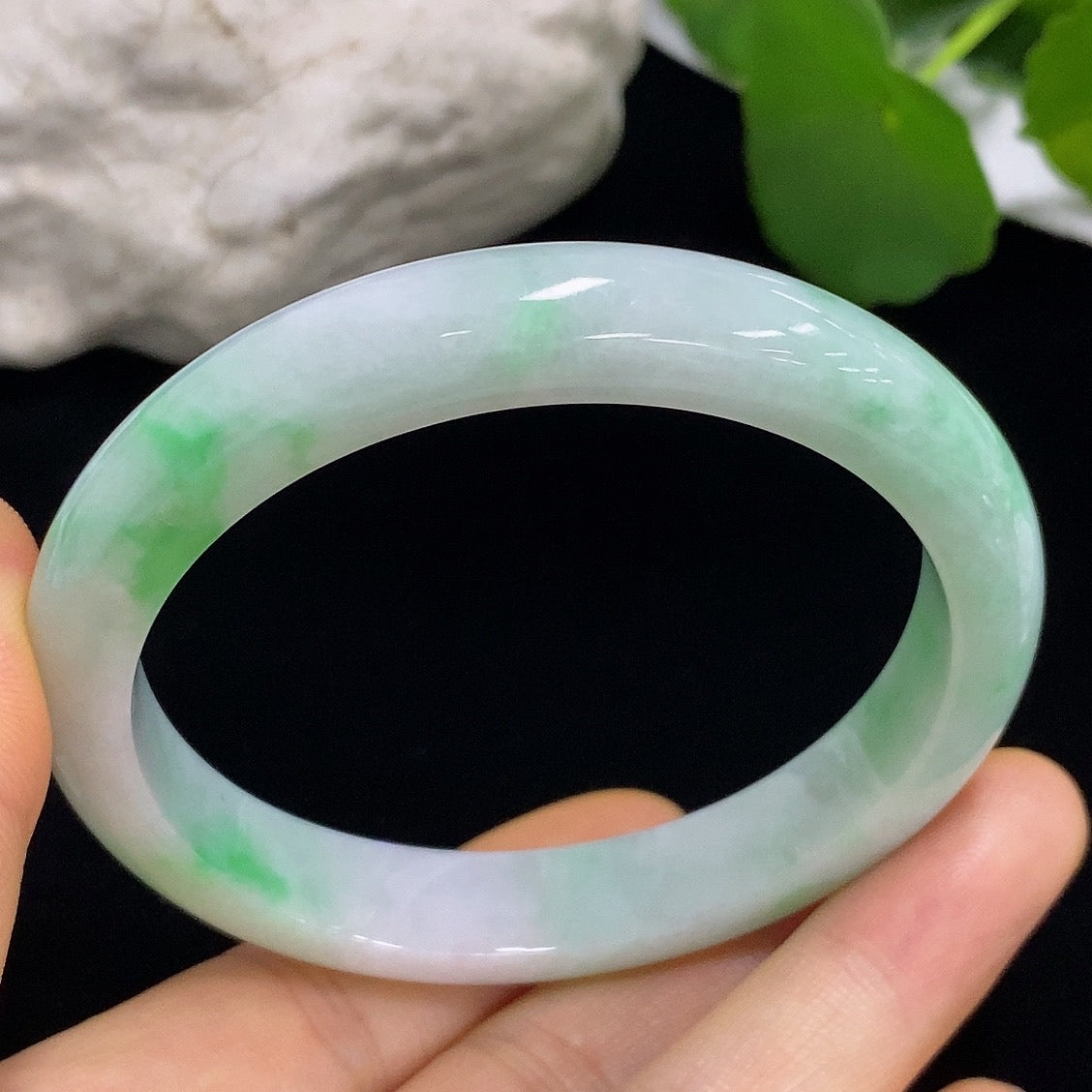 Close-up of a HKHQ jadeite round bangle with size 57.3 and weight 43.82g, showcasing the smooth, polished jade surface.