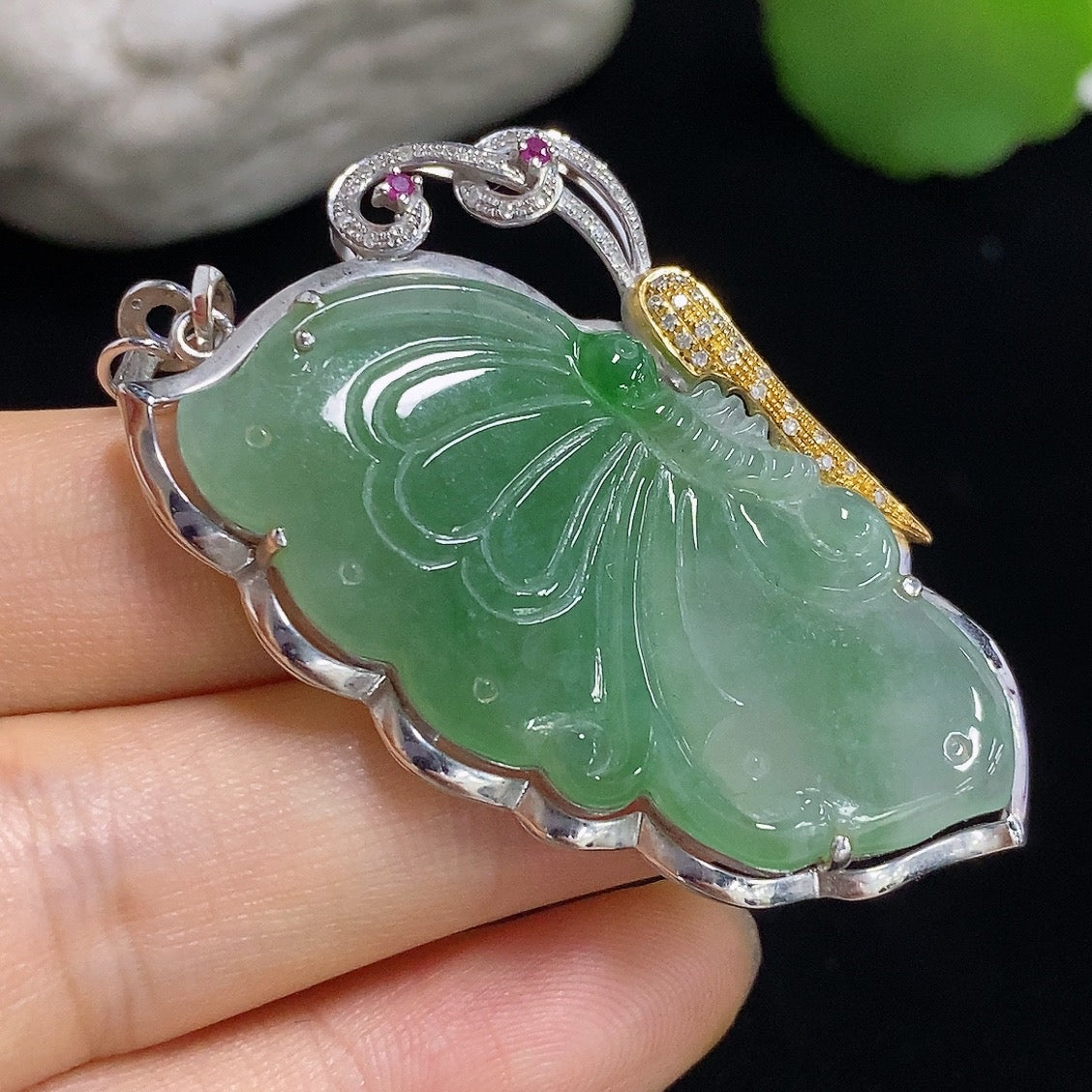 Jadeite butterfly pendant with 18k gold accents, diamond details, and a smooth green jade surface on a jewelry display.