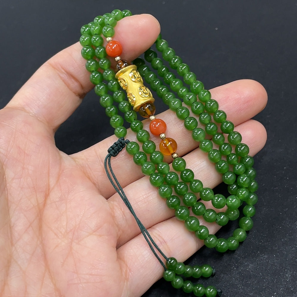 Hetian jade beaded necklace with smooth round beads, natural green color, and subtle variations, styled on a white background.